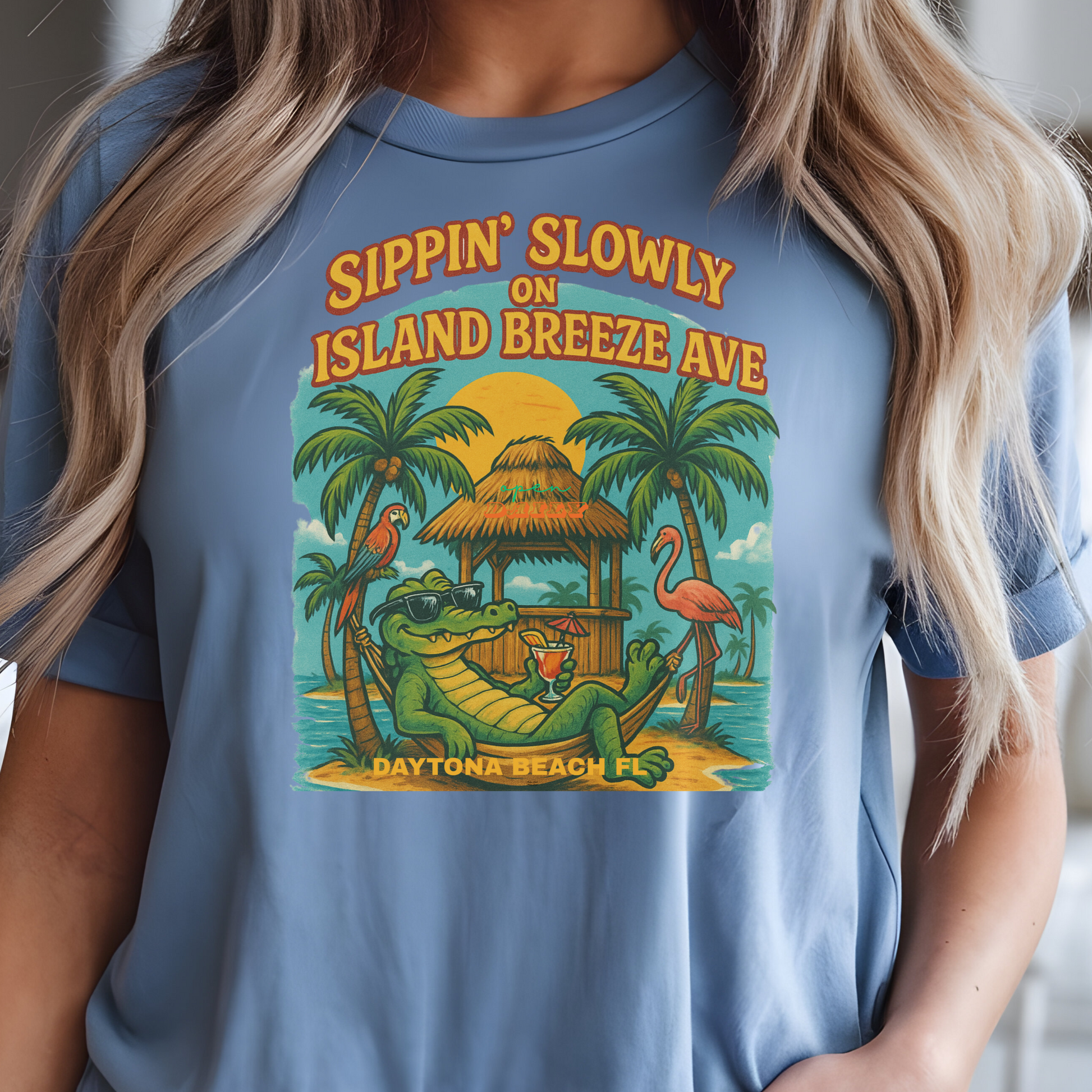 Person wearing a blue t-shirt with a tropical design and text in a living room.