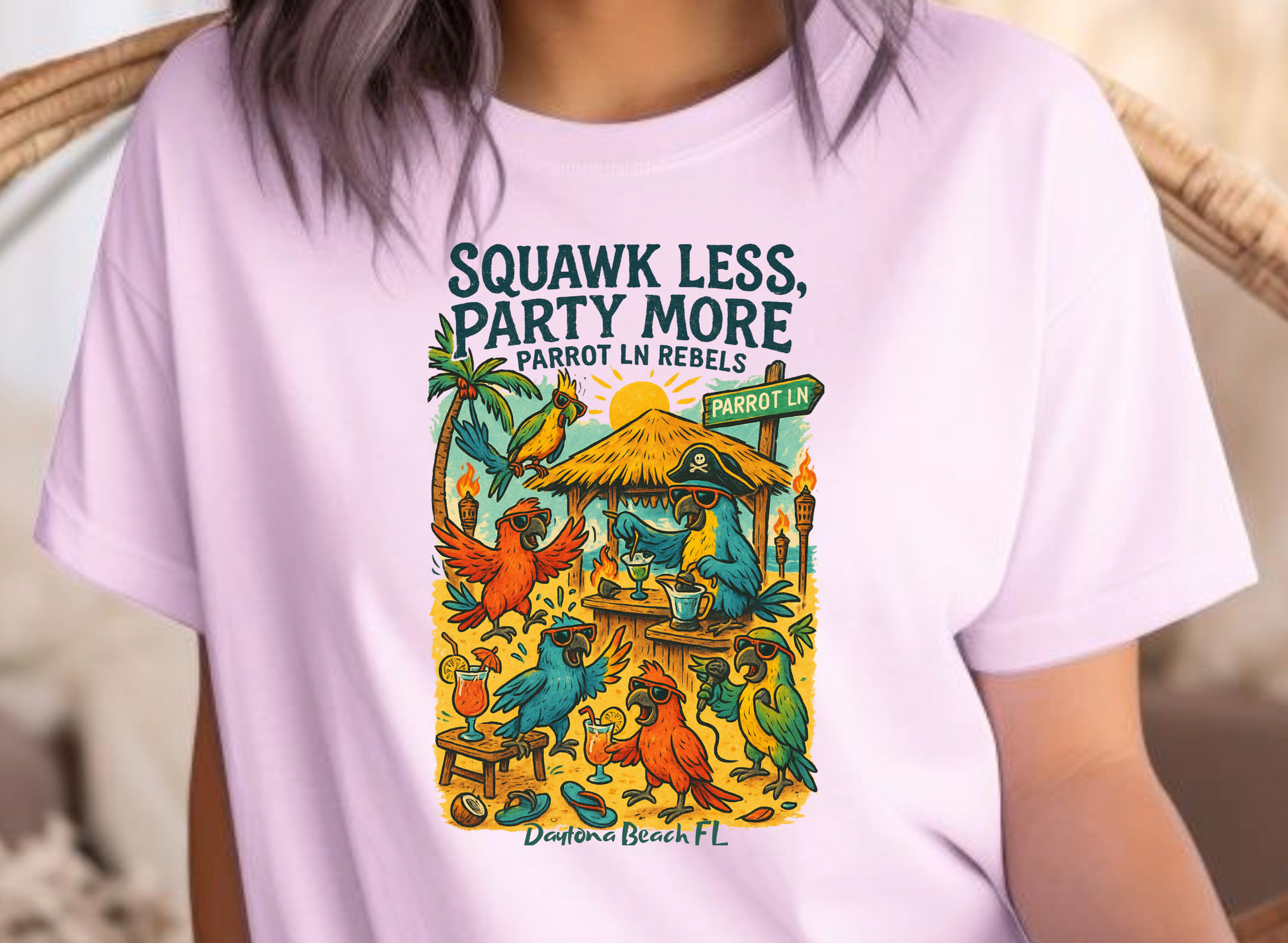 Person wearing a light purple t-shirt with a colorful graphic and text, sitting on a wicker chair.