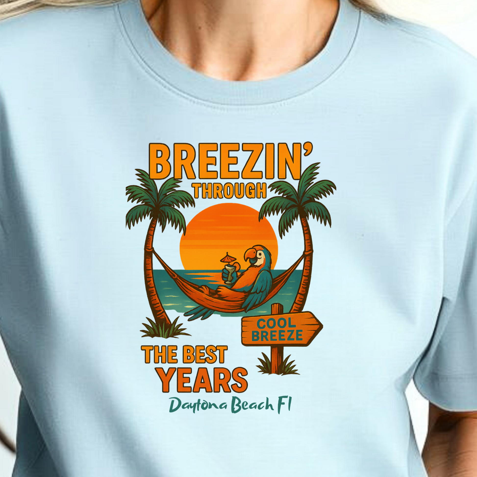 Person wearing a light blue t-shirt with a tropical design and text.