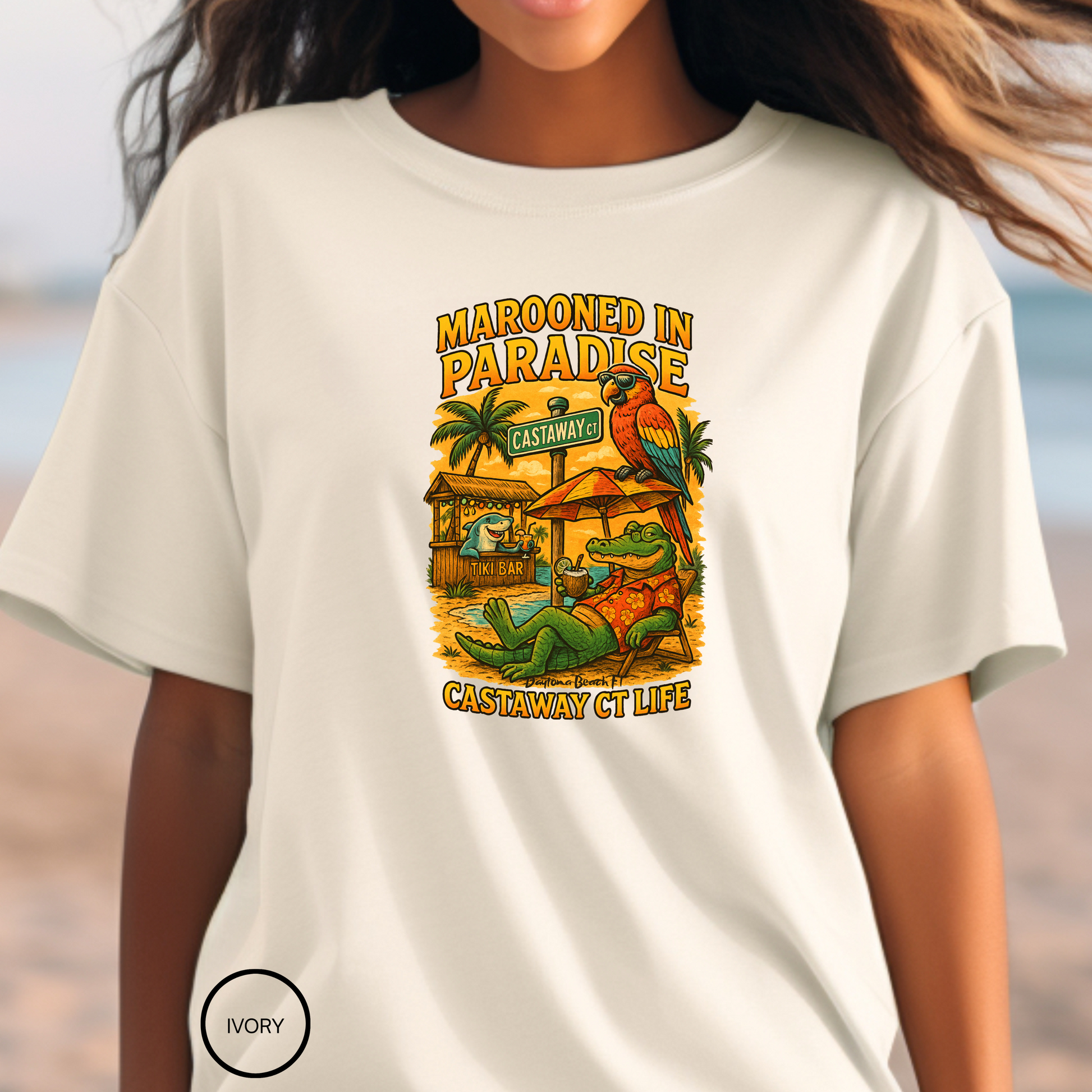 Person wearing a white t-shirt with a colorful graphic design on a beach.