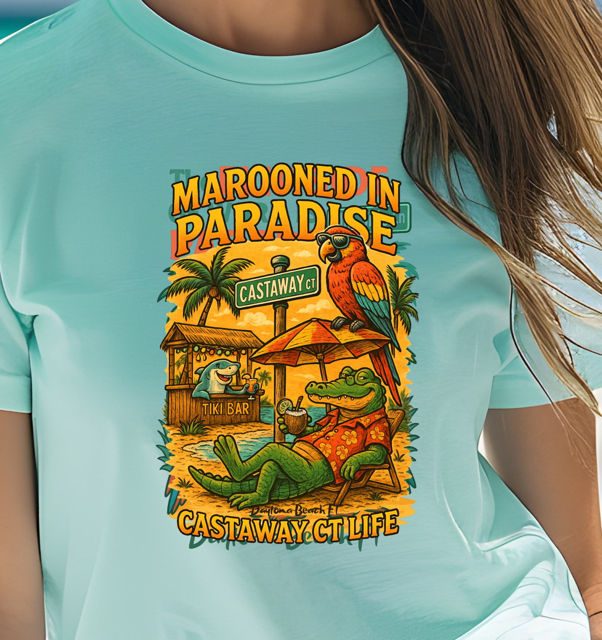 Person wearing a light blue t-shirt with a colorful graphic design on a beach.