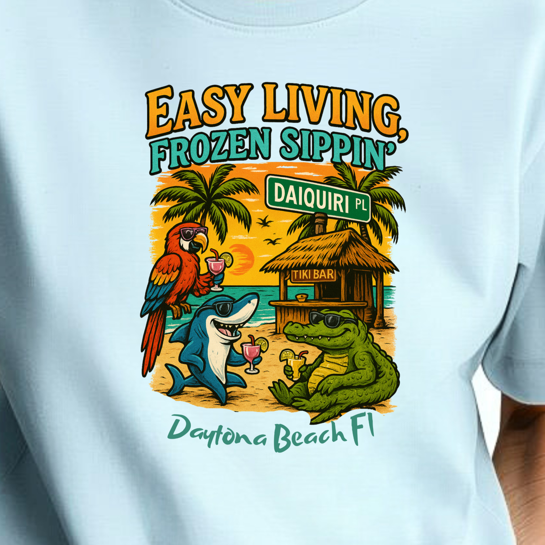 Person wearing a light blue t-shirt with a tropical-themed graphic and text.