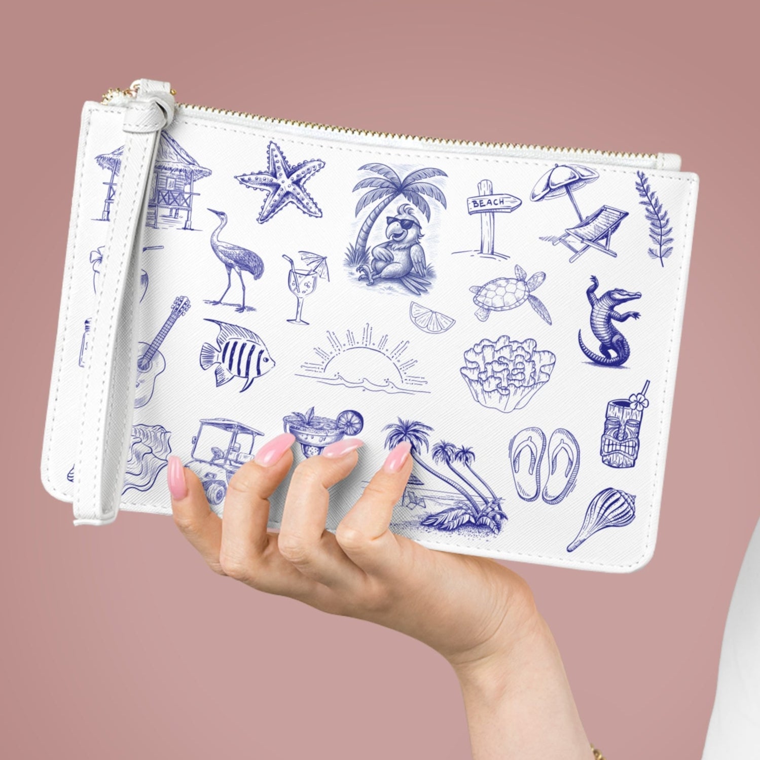 Hand holding a white pouch with blue illustrations against a pink background